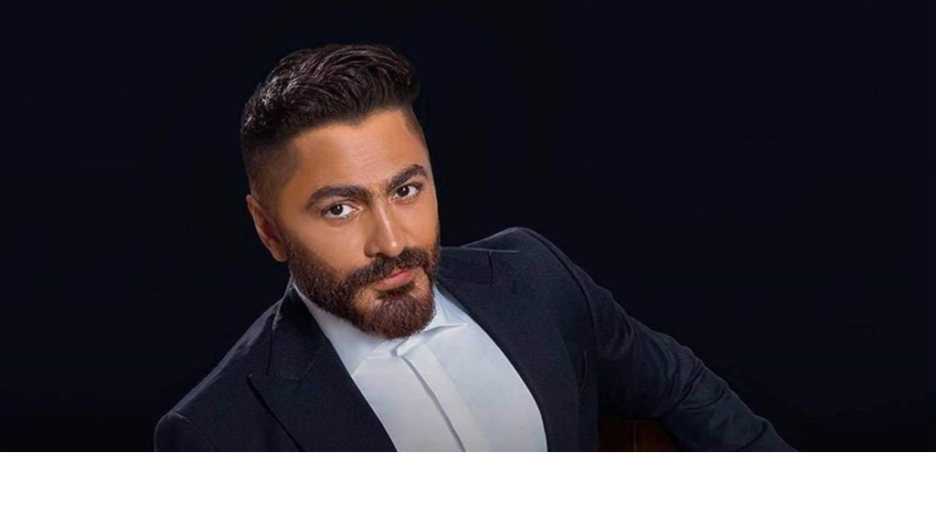 أطل بشعر مستعار وسلاسل ذهبية ضخمة.. تامر حسني يُفاجئ الجمهور بشكله الغريب (فيديو)